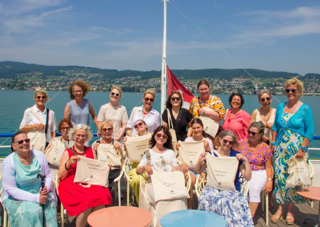 Eine Gruppe an Bord eines Schiffs hält Stofftaschen mit yarni Aufdruck in die Kamera.